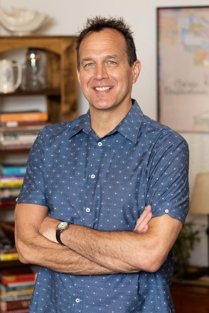 A man standing in front of books and smiling.